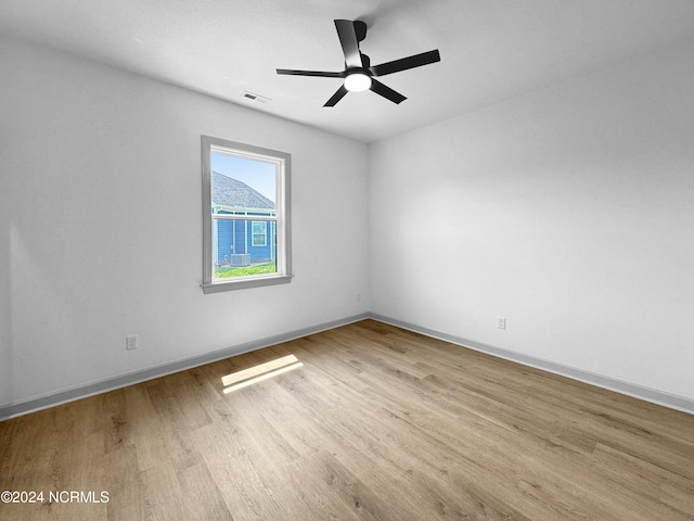 empty room featuring ceiling fan, wood finished floors, visible vents, and baseboards