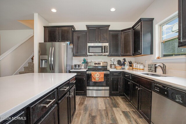 kitchen featuring appliances with stainless steel finishes, light countertops, a sink, and wood finished floors