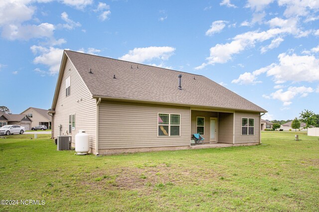 rear view of property featuring a shingled roof, central AC unit, a lawn, and a patio