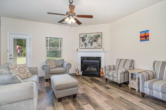 living area with wood finished floors, a ceiling fan, baseboards, visible vents, and a high end fireplace