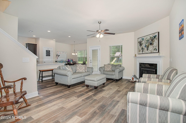 living room with light wood finished floors, baseboards, a ceiling fan, a fireplace, and recessed lighting