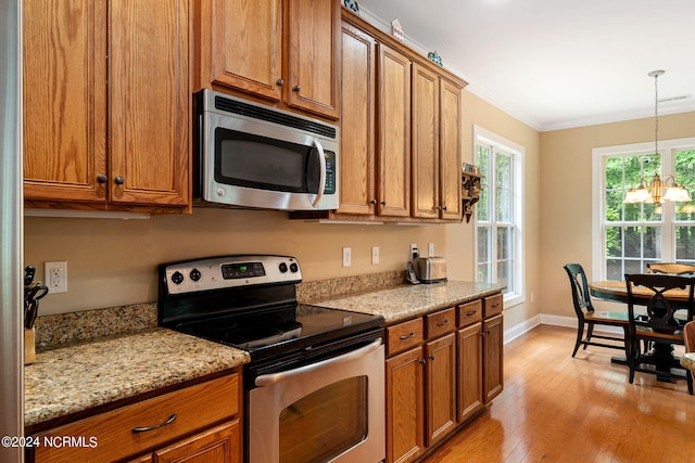 kitchen featuring light stone counters, light hardwood / wood-style flooring, a notable chandelier, crown molding, and appliances with stainless steel finishes