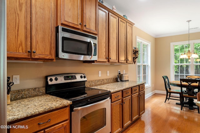 227 October Glory Dr, Wallace, NC 28466 - kitchen featuring appliances with stainless steel finishes, brown cabinets, light wood-style flooring, a chandelier, and ornamental molding