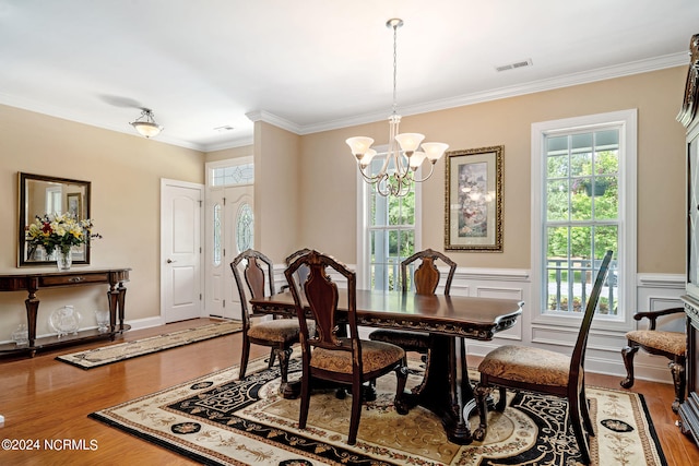 dining room with crown molding, a notable chandelier, and hardwood / wood-style flooring