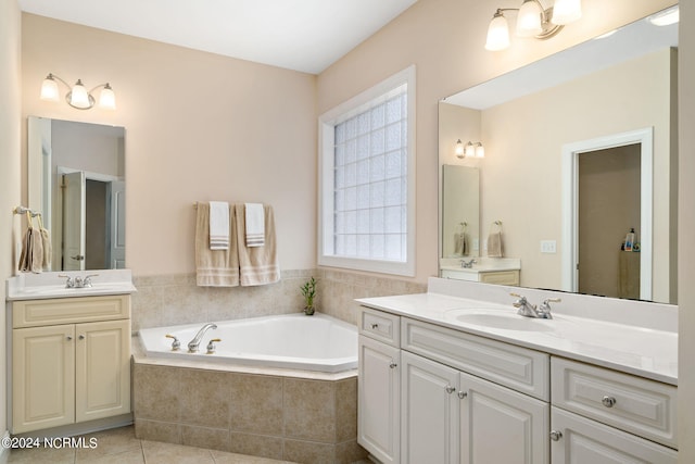 bathroom with tile patterned flooring, a relaxing tiled tub, and vanity