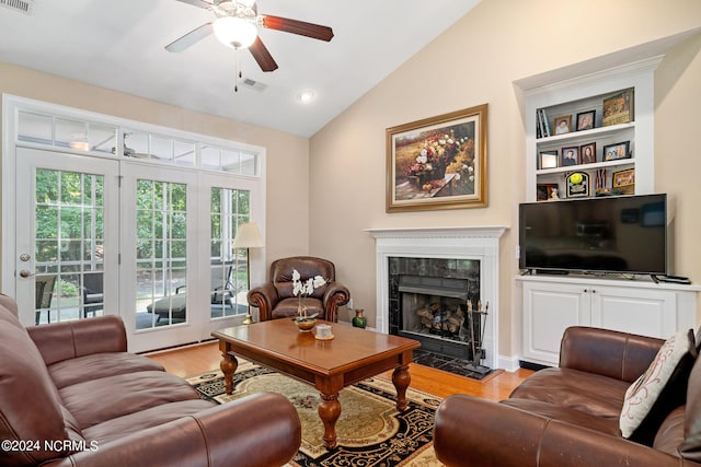 living room with ceiling fan, light wood-type flooring, a fireplace, and vaulted ceiling