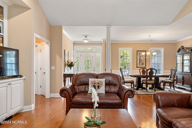 living room featuring a chandelier, decorative columns, light hardwood / wood-style flooring, and crown molding