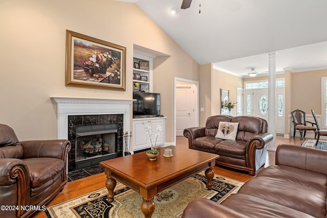 living room featuring hardwood / wood-style floors, vaulted ceiling, ceiling fan, built in features, and a fireplace