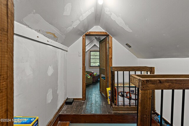 hall with lofted ceiling and dark wood-type flooring