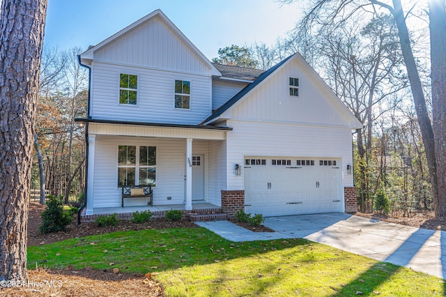 view of front of house with covered porch, a front yard, and a garage