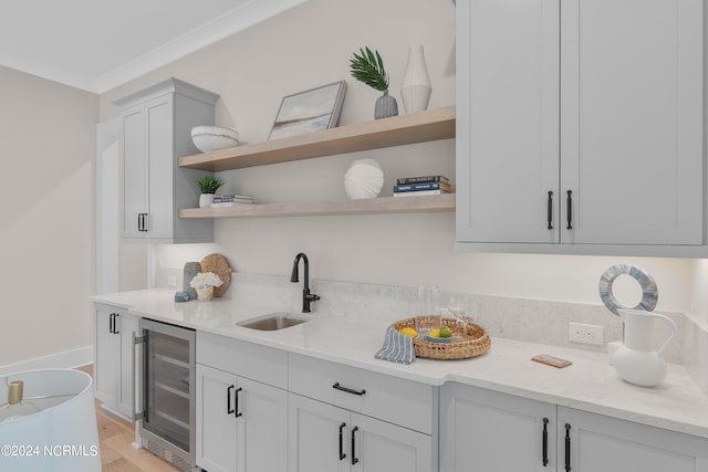 kitchen featuring light stone counters, wine cooler, light hardwood / wood-style floors, and sink