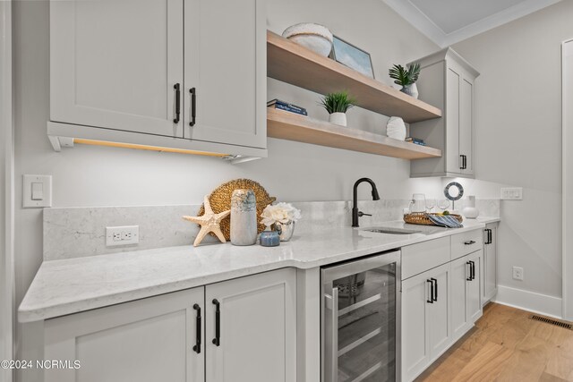 kitchen featuring light hardwood / wood-style floors, light stone counters, sink, and beverage cooler