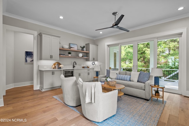 living room with ceiling fan, sink, wine cooler, crown molding, and light hardwood / wood-style floors