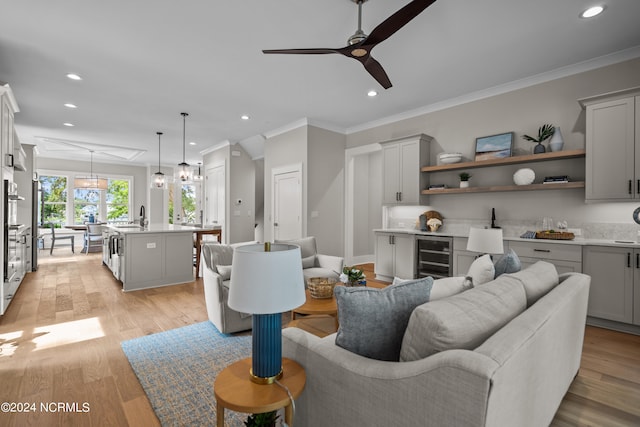 living room with light hardwood / wood-style floors, wine cooler, ceiling fan, and crown molding