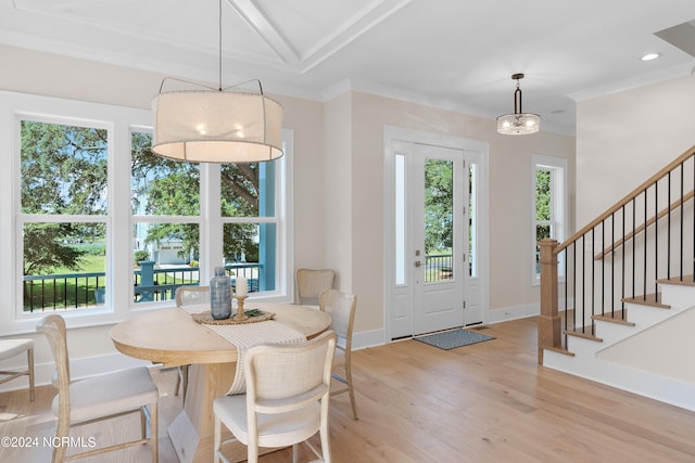 dining area with light wood-type flooring, crown molding, and a wealth of natural light