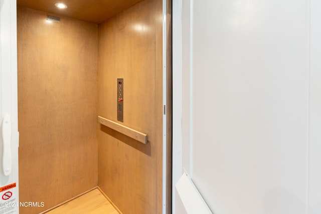 details featuring elevator and hardwood / wood-style flooring