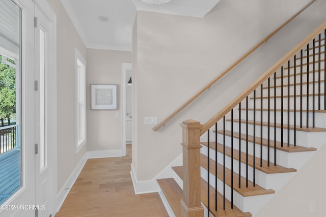 stairs with hardwood / wood-style flooring and crown molding