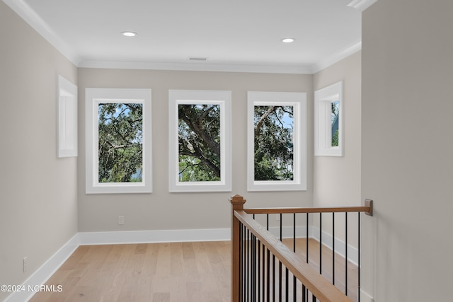 hallway with plenty of natural light, ornamental molding, and light wood-type flooring