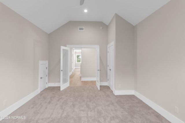 unfurnished bedroom with a closet, lofted ceiling, light carpet, and french doors