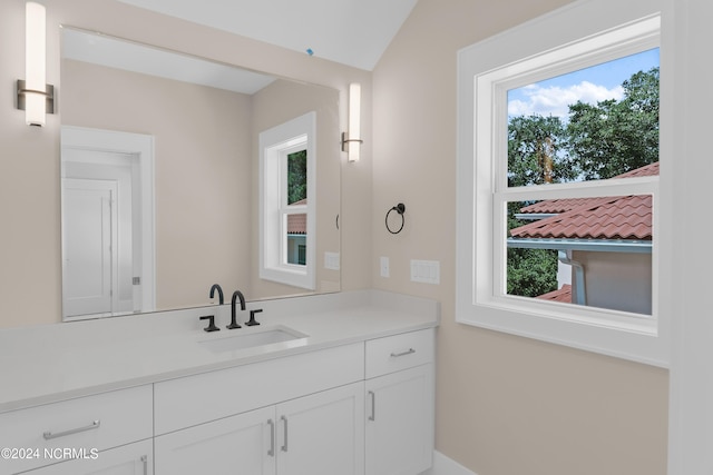 bathroom featuring vanity, a healthy amount of sunlight, and vaulted ceiling