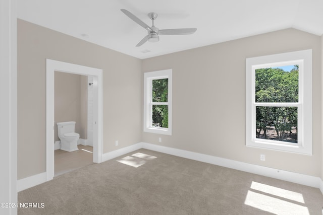 unfurnished bedroom with ceiling fan, vaulted ceiling, light colored carpet, and ensuite bath