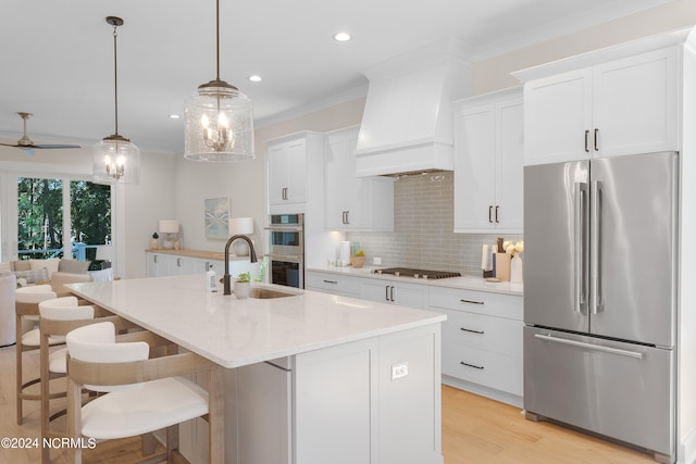 kitchen featuring white cabinets, stainless steel appliances, a center island with sink, and custom exhaust hood