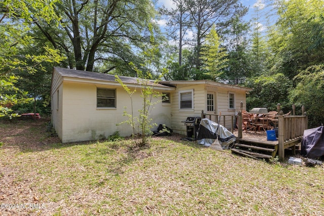 rear view of house with a lawn and a wooden deck