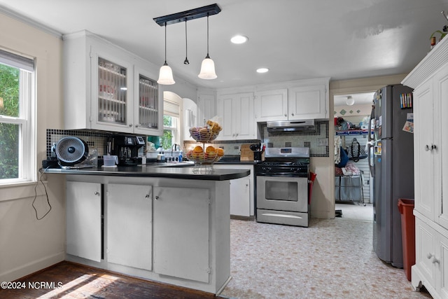 kitchen with stainless steel appliances, a wealth of natural light, kitchen peninsula, and tasteful backsplash