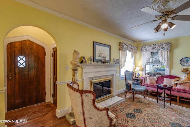 entrance foyer featuring ornamental molding, arched walkways, a textured ceiling, and wood finished floors