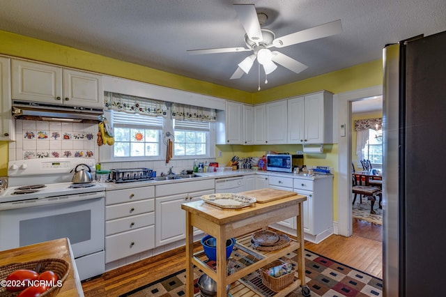 kitchen with white appliances, light countertops, a sink, and under cabinet range hood