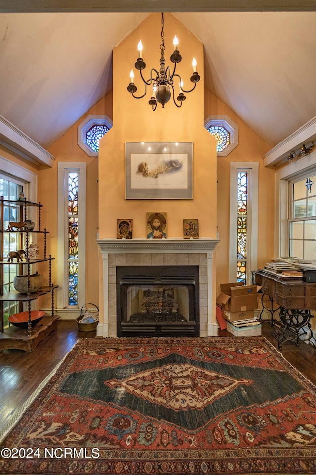 living area with a chandelier, a fireplace, high vaulted ceiling, and wood finished floors