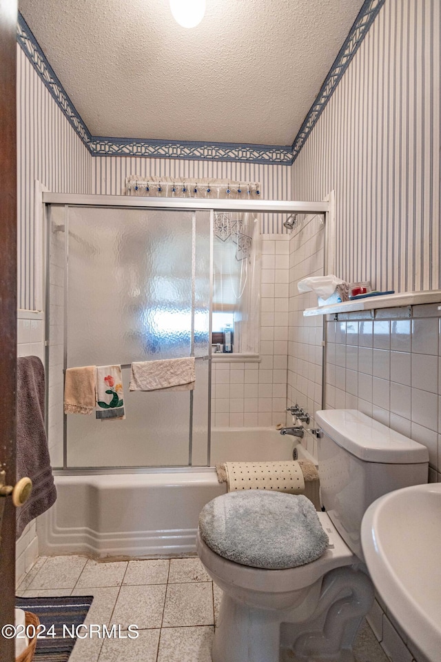 bathroom with a textured ceiling, enclosed tub / shower combo, toilet, and tile patterned floors