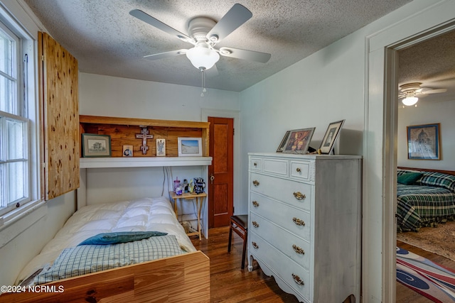 bedroom with dark wood-style floors, a textured ceiling, and a ceiling fan