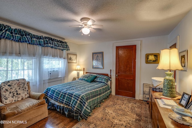 bedroom featuring a ceiling fan, cooling unit, a textured ceiling, and wood finished floors