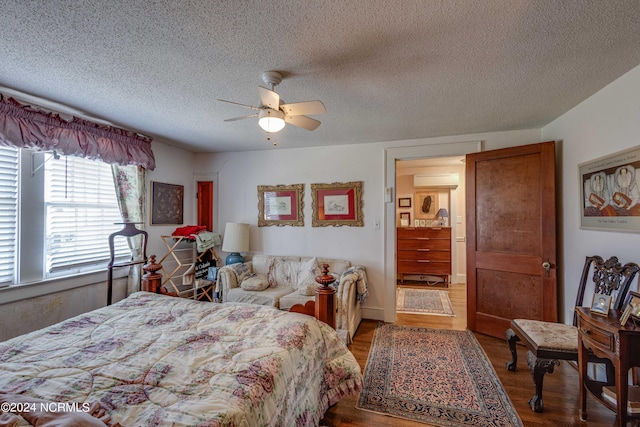 bedroom featuring an AC wall unit, ceiling fan, a textured ceiling, and wood finished floors