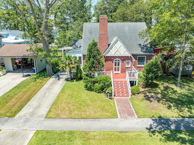 view of front of house featuring brick siding, a chimney, a shingled roof, stairway, and a front lawn