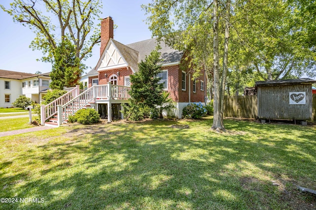 view of front facade with a chimney, stairway, an outbuilding, a front lawn, and brick siding