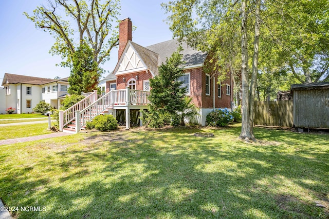 view of front of property featuring a chimney, stairs, a deck, a front lawn, and brick siding