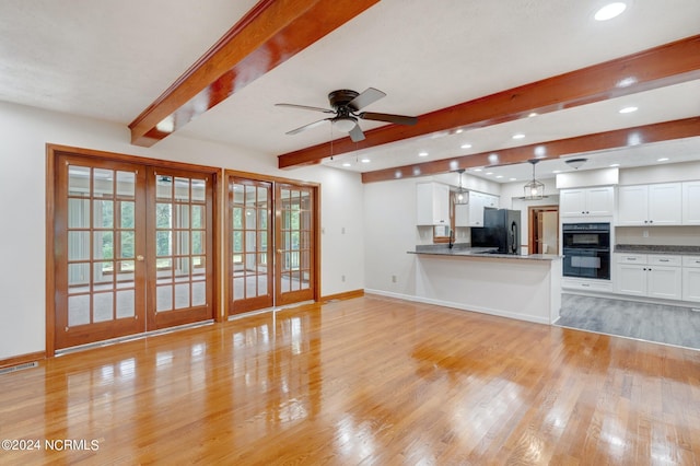 unfurnished living room with ceiling fan, beam ceiling, french doors, and light hardwood / wood-style flooring