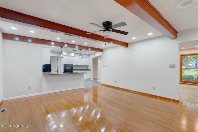 unfurnished living room featuring beam ceiling, ceiling fan, and light hardwood / wood-style floors