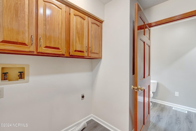 laundry room featuring cabinets, hardwood / wood-style flooring, hookup for a washing machine, and electric dryer hookup