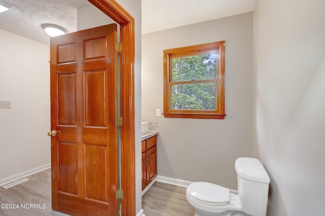 bathroom featuring a textured ceiling, hardwood / wood-style flooring, vanity, and toilet