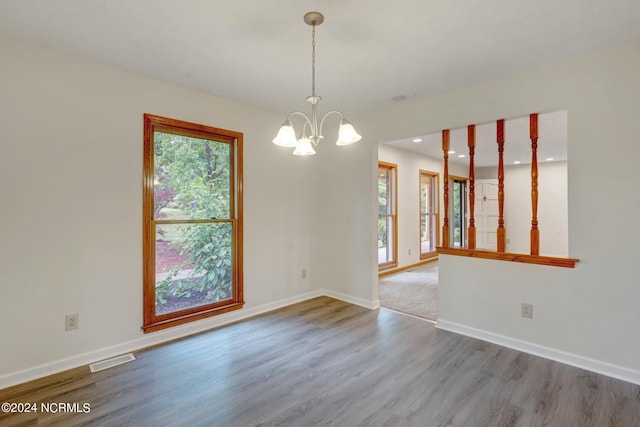 unfurnished room with wood-type flooring and an inviting chandelier