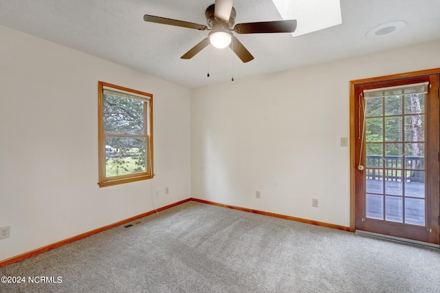 carpeted spare room with a skylight, ceiling fan, and a wealth of natural light