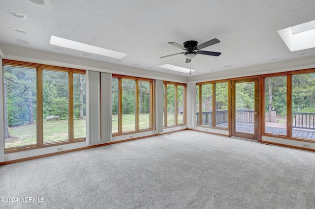 unfurnished sunroom with plenty of natural light, ceiling fan, and a skylight