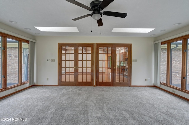 unfurnished room with plenty of natural light, french doors, carpet, and a skylight