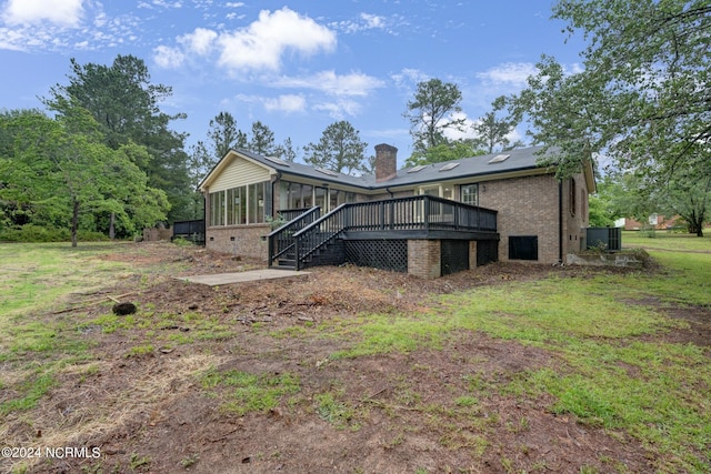 rear view of house featuring a sunroom, a wooden deck, and a yard