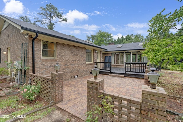 back of property with a deck and a patio area