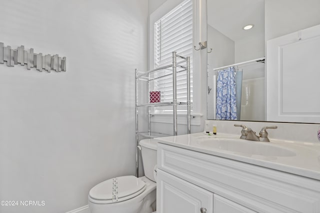 bathroom with curtained shower, vanity, and toilet