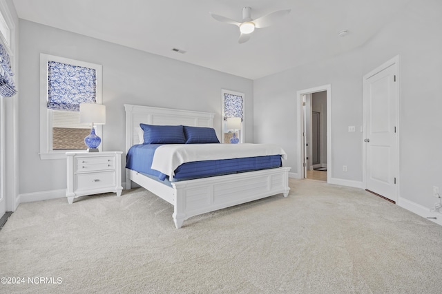 carpeted bedroom featuring multiple windows and ceiling fan